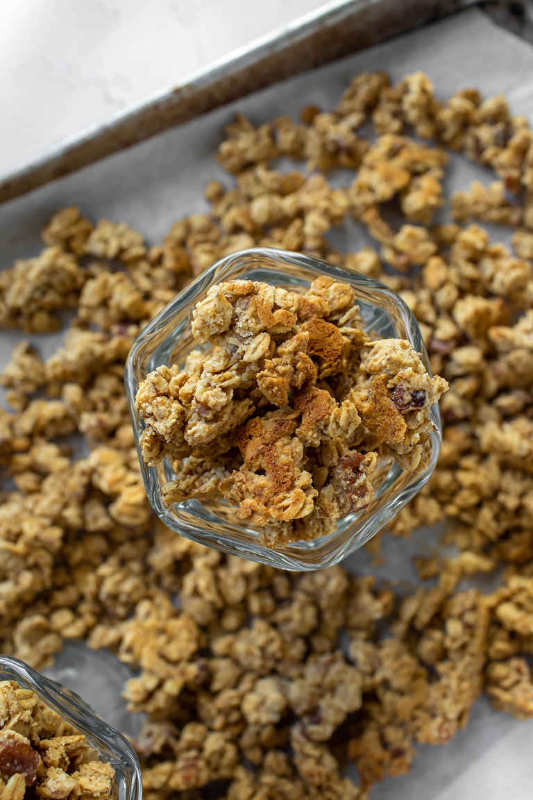 overhead view of glass bowl of vegan granola on top of tray of granola