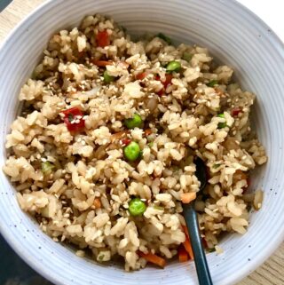 vegan fried rice in white bowl with black spoon