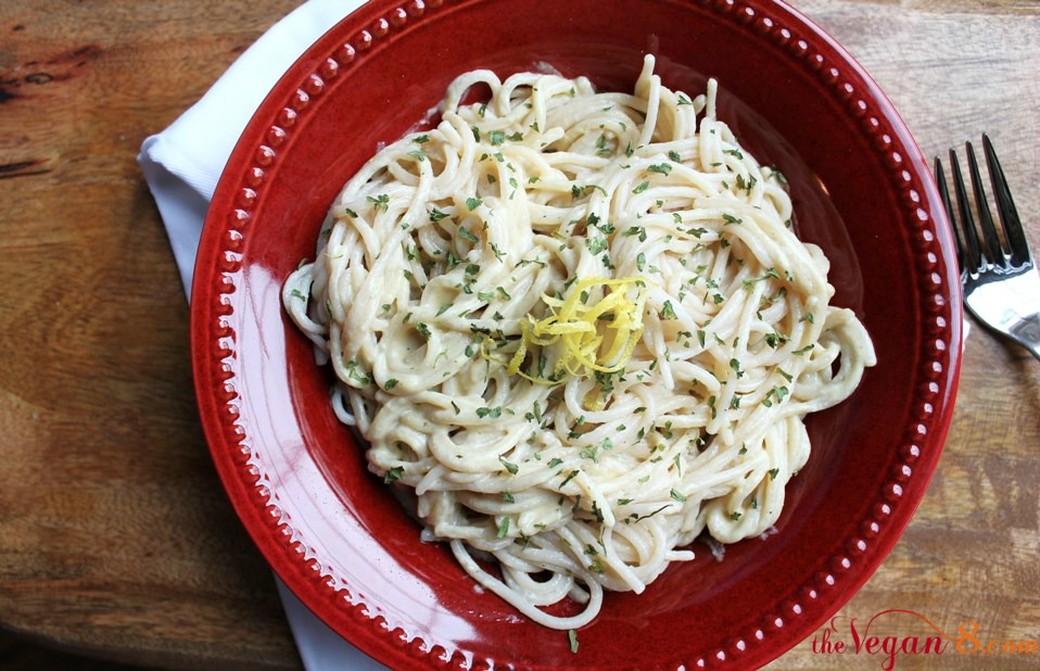 red bowl with vegan garlic alfredo sauce and pasta on wooden table