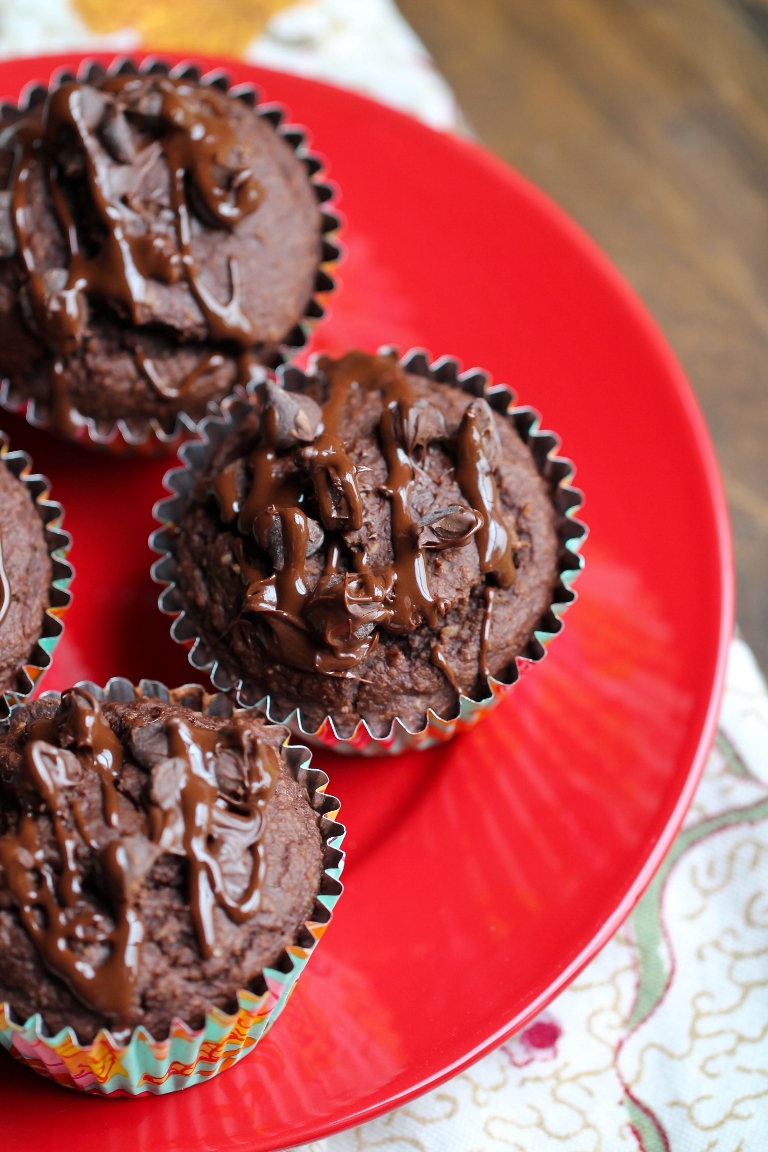 vegan chocolate muffins with chocolate sauce on top on red plate