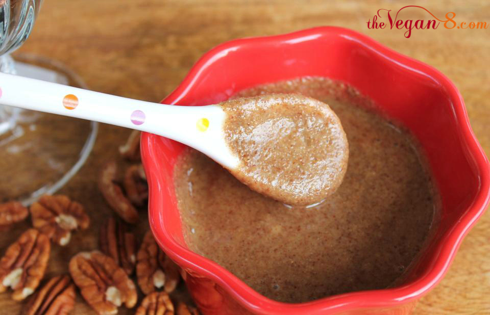 spoon dipping into red bowl of pecan butter