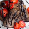 folded over vegan chocolate crepes with strawberries and chocolate sauce