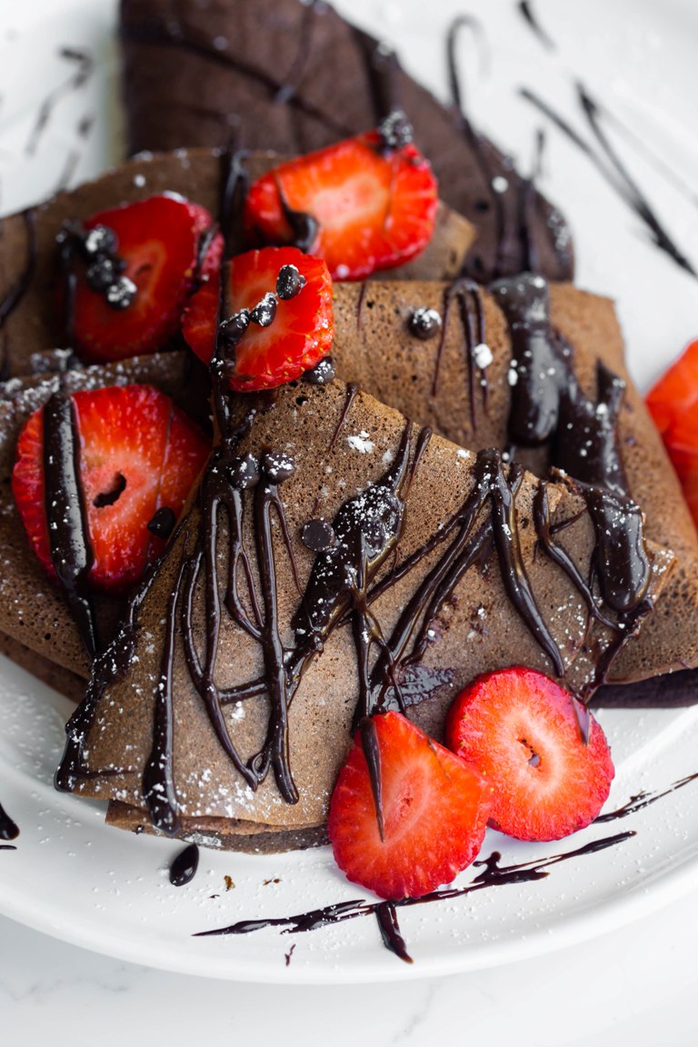 folded over vegan chocolate crepes with strawberries and chocolate sauce