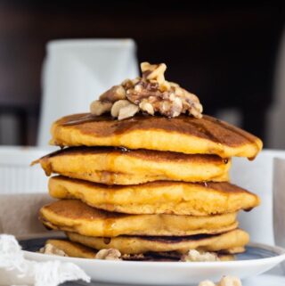 stack of sweet potato pancakes with syrup and walnuts on top