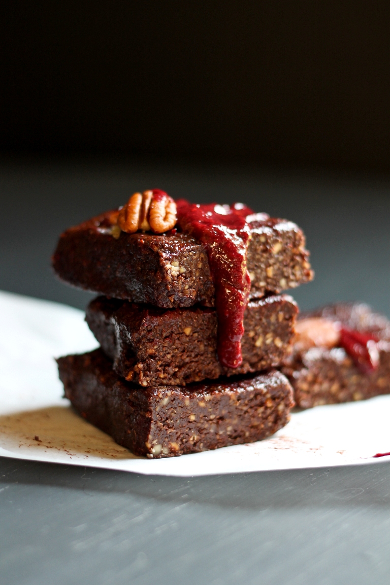 stack of 3 vegan no bake brownies with raspberry coulis dripping down