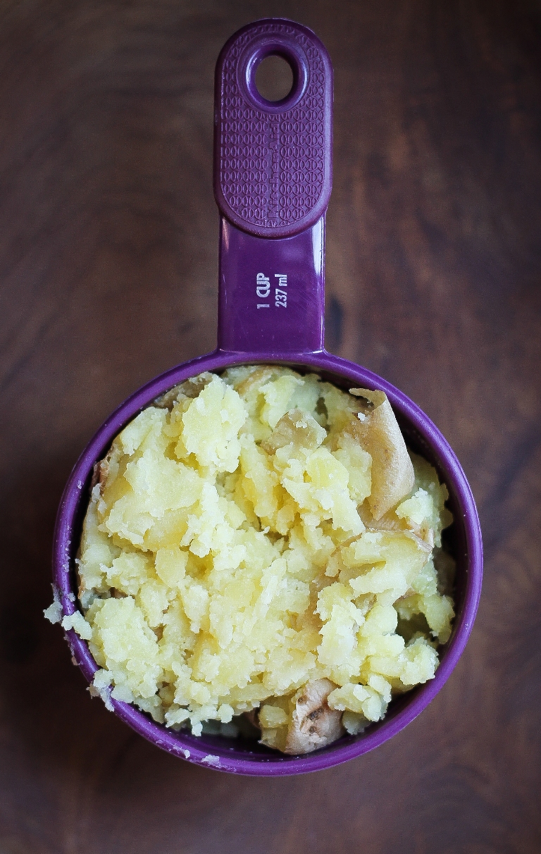 measuring cup holding cooked mashed potatoes