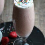 strawberry milkshake in tall glass with sprinkles