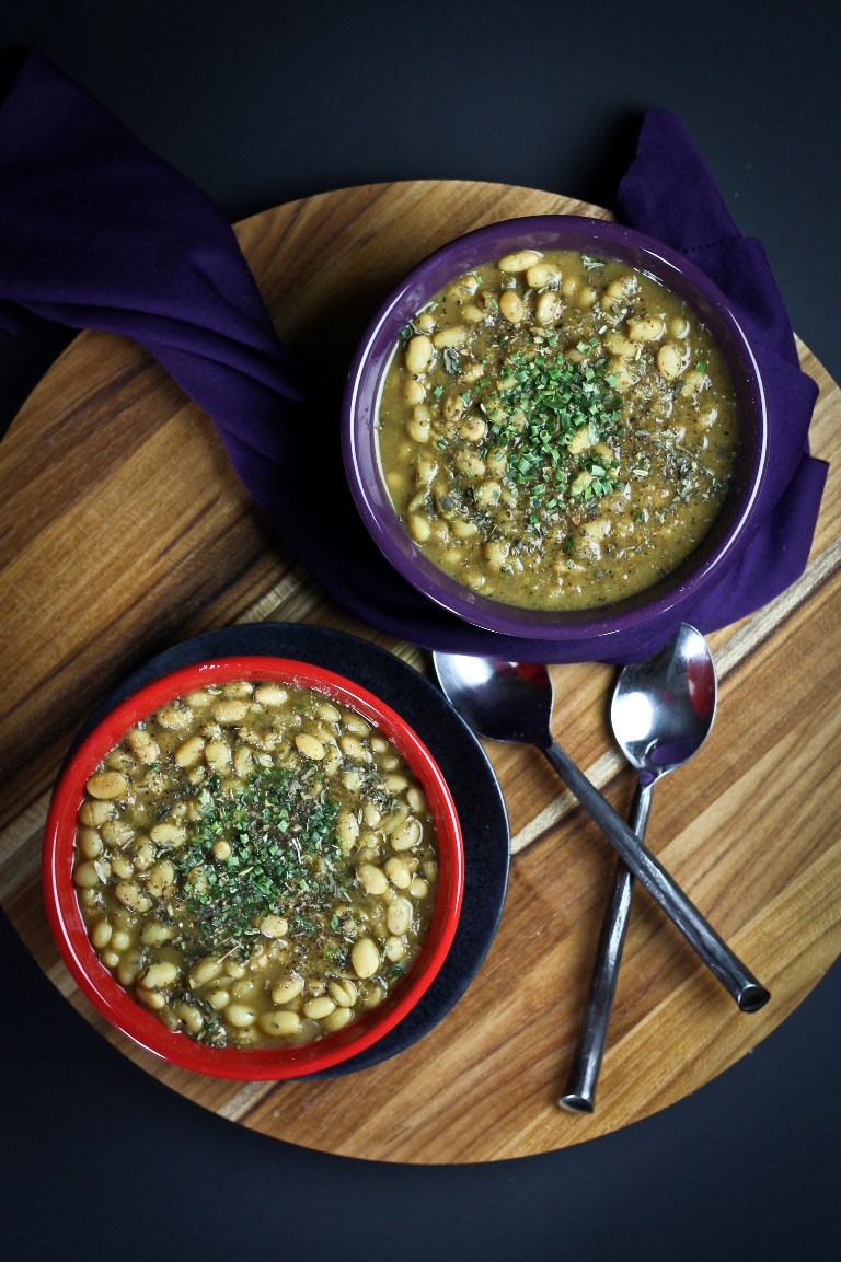 2 bowls on wood platter of vegan white bean chili with spoons