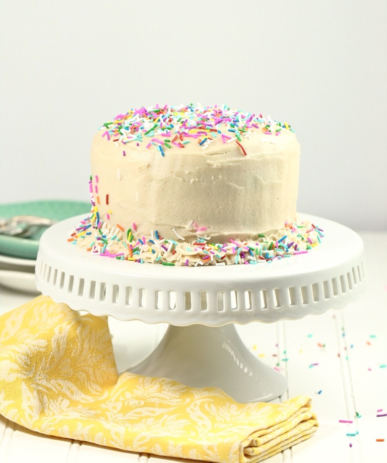 Vegan funfetti cake on white cake stand with yellow napkin