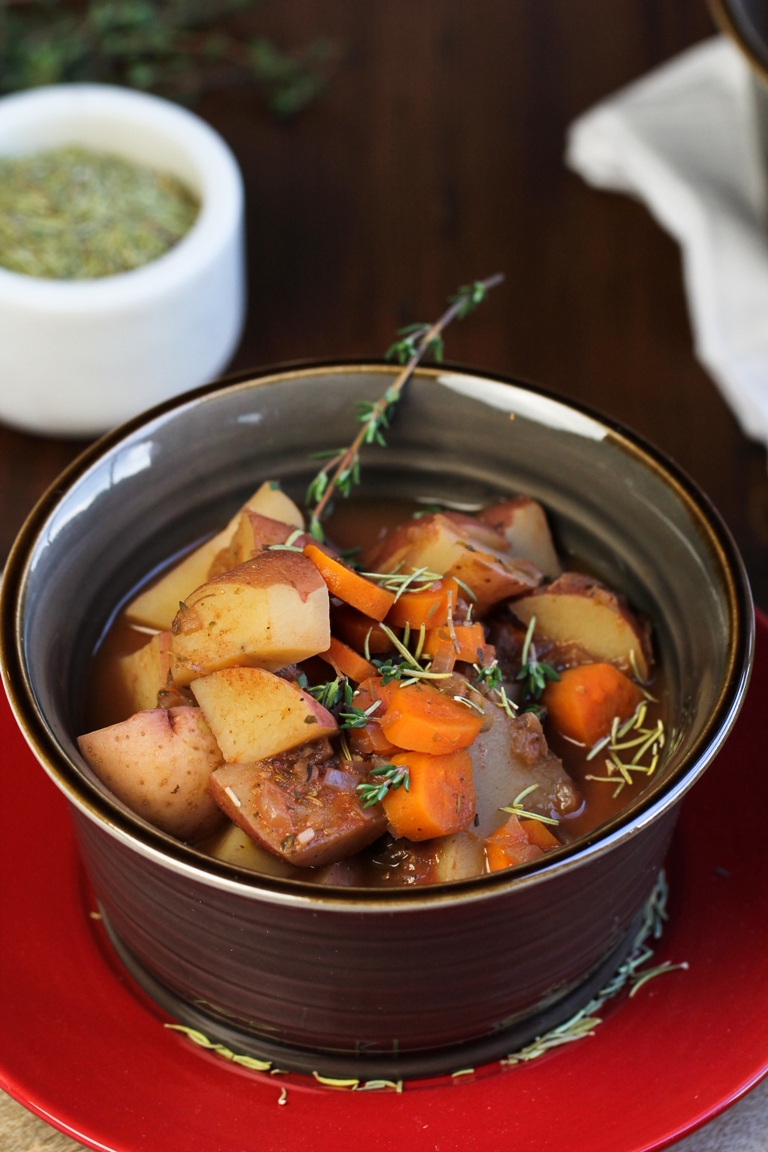 vegan stew in brown bowl with fresh thyme
