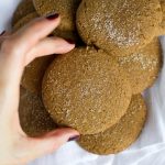 hand grabbing vegan gingersnap cookie from bowl