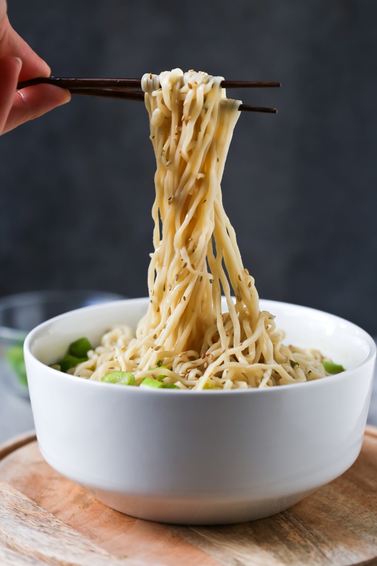 chopsticks holding vegan ramen noodles out of bowl 