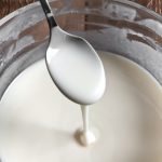 glass bowl of coconut butter with some dripping off spoon