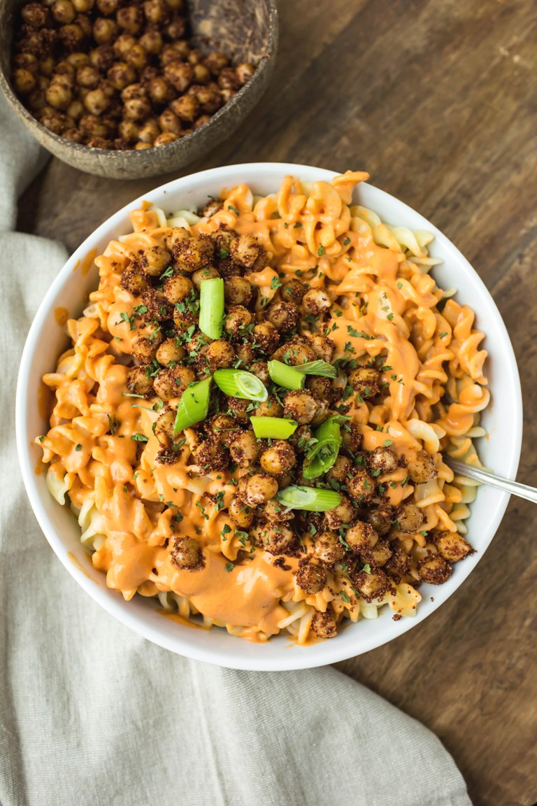 Plate of fusilli pasta with vegan pimento cream sauce, chickpeas and green onions on top.