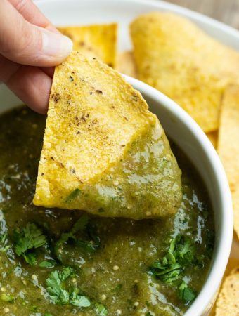 Hand dipping chip in roasted tomatillo salsa verde