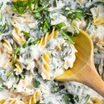 closeup of wood spoon in pasta cream sauce