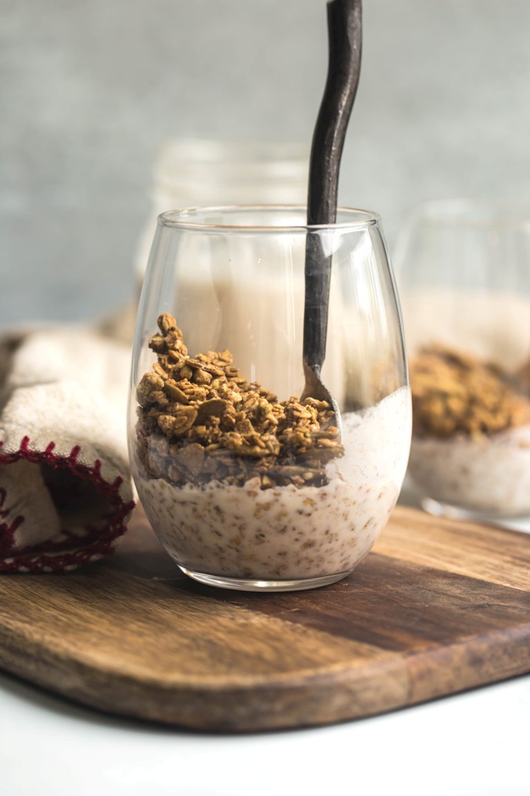 granola in glass with almond milk on wood board