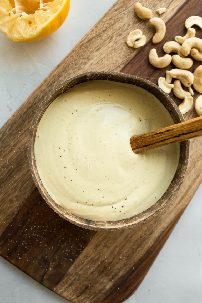 wooden bowl of vegan caesar dressing with cashews on side