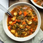 potato carrot tomato soup in white bowl on wooden board
