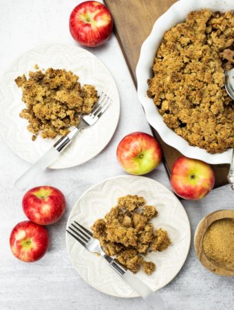 overhead of 2 plates of vegan apple crisp with red apples
