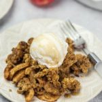 apple crisp with dairy-free whip cream on white plate