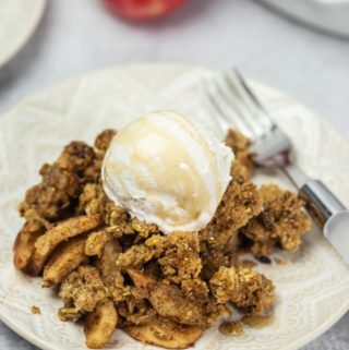 apple crisp with dairy-free whip cream on white plate