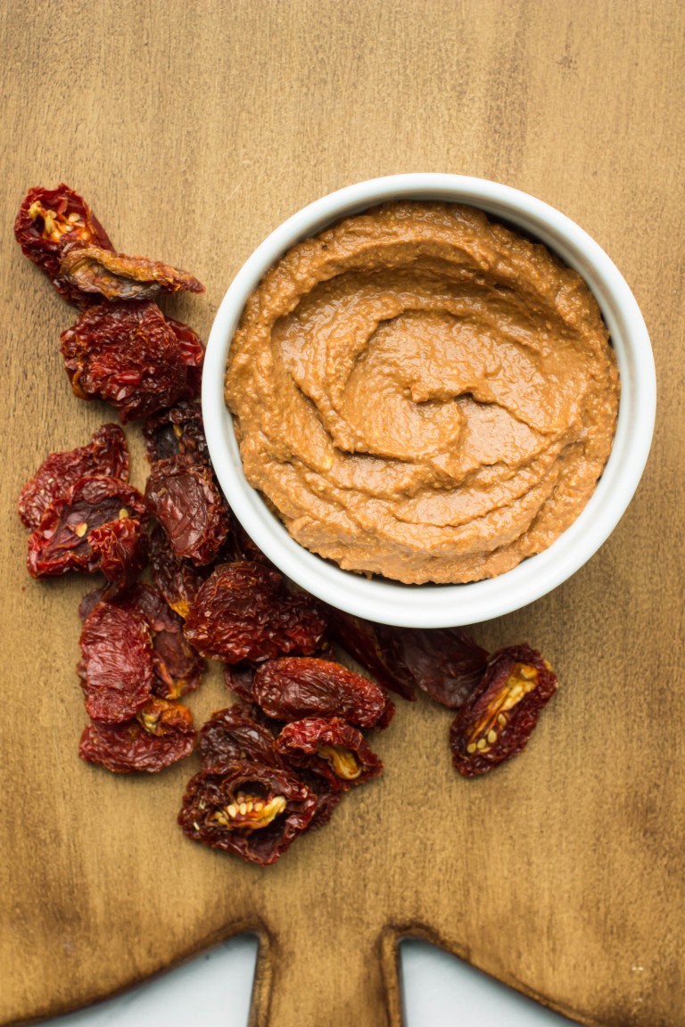sundried tomato spread in white bowl with extra sundried tomatoes