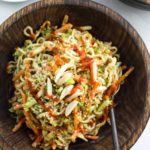 wooden bowl with asian ramen noodle salad with hot sauce drizzle