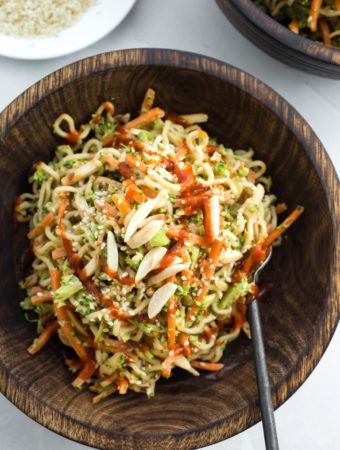 wooden bowl with asian ramen noodle salad with hot sauce drizzle
