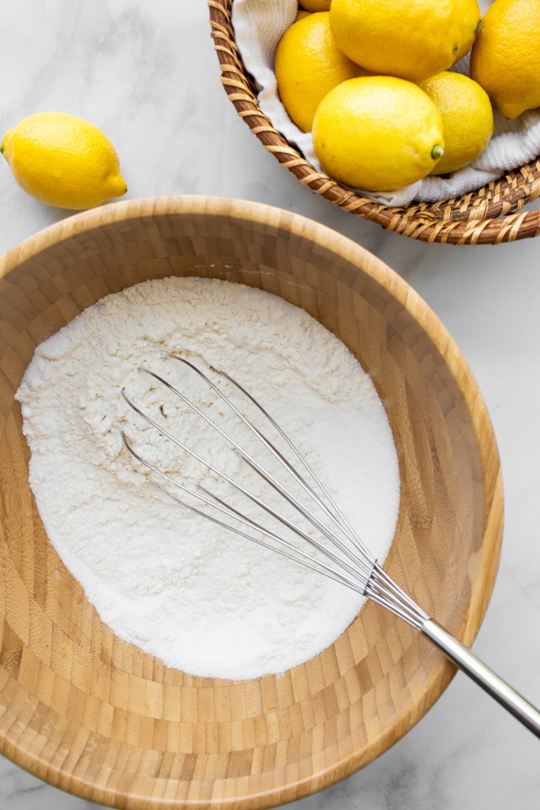 lemon cake dry ingredients in wooden bowl with whisk