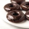 several vegan chocolate donuts on white marble