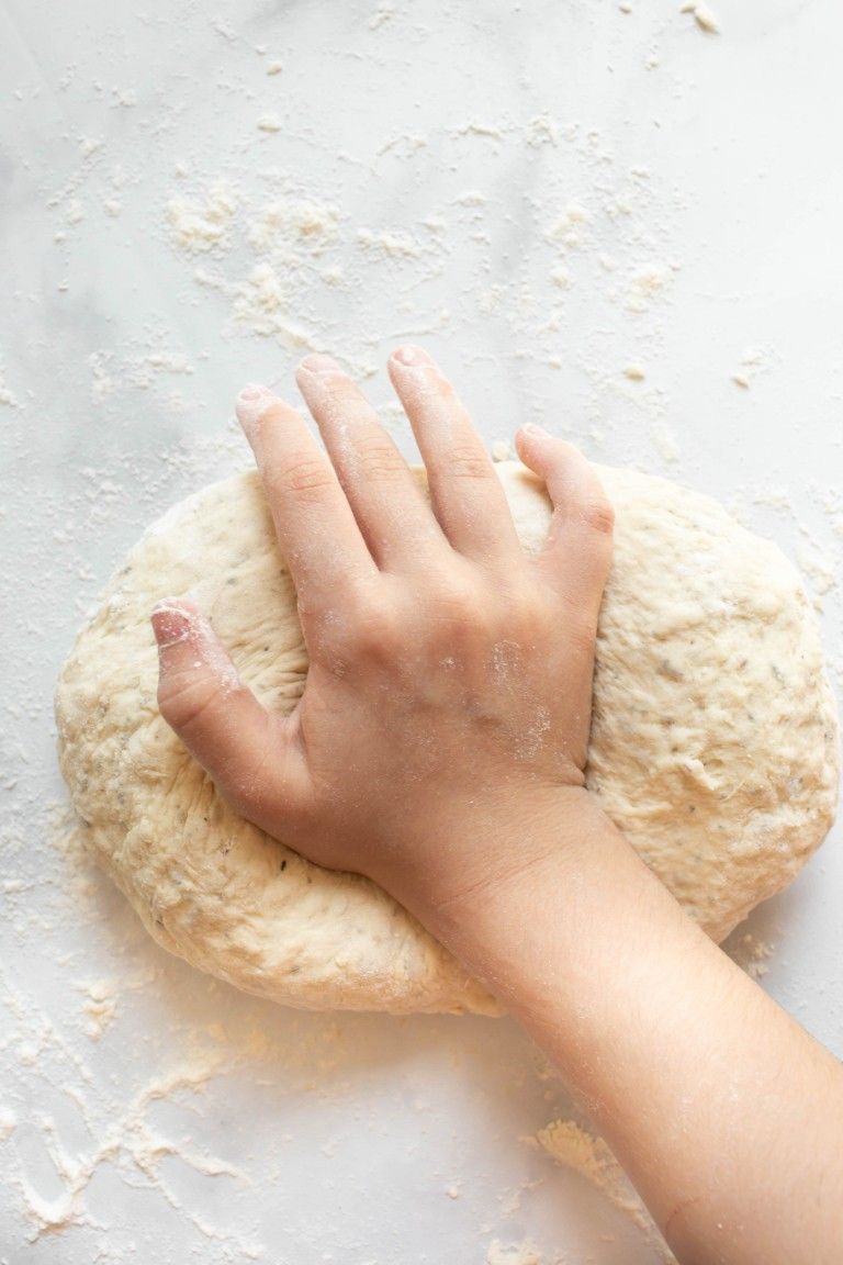 hand kneading dough on marble surface