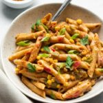 bowl of Cajun pasta on white surface with fork in bowl