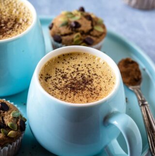 blue mug of vegan pumpkin spice latte with cinnamon sprinkles on top