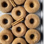 overhead view of several baked vegan apple cider donuts with cinnamon sticks