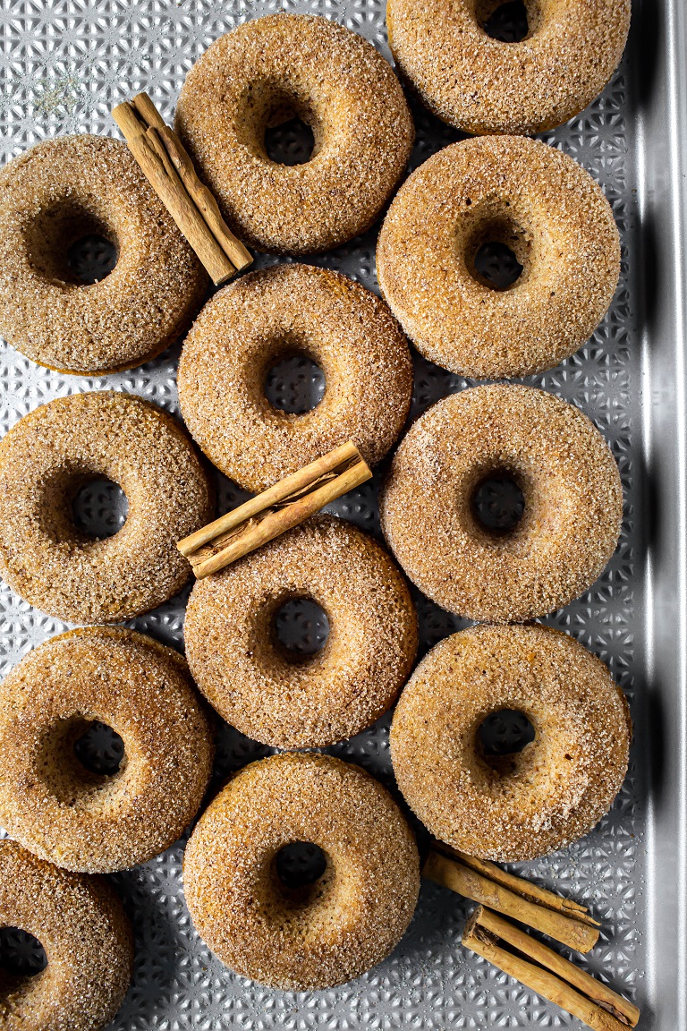 overhead view of several baked vegan apple cider donuts with cinnamon sticks