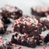 2 vegan peppermint brownies stacked on top of each other on white paper