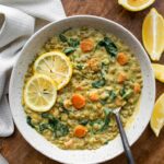 overhead view of white bowl with creamy lentil soup and lemon slices