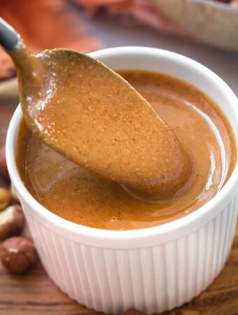 closeup of roasted hazelnut butter in white bowl with spoon