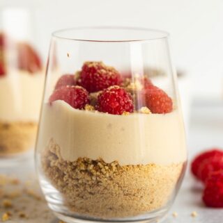 up close image of glass with vegan cheesecake pudding and raspberries