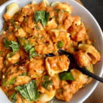white bowl of vegan cream cheese tomato pasta with fork