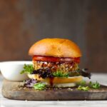 closeup shot of vegan teriyaki veggie burger on wood platter