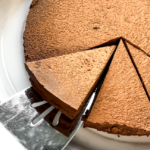 spatula sliding into fudge cake on white round platter