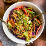large white bowl of vegan thai peanut salad with large gold spoon and fork