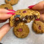 hands with pink nails holding closeup vegan monster cookie