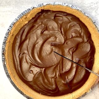overhead shot of knife slicing vegan chocolate pumpkin pie